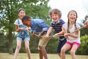 four children smiling pulling tug-of-war rope - Children's activity ideas for Summer